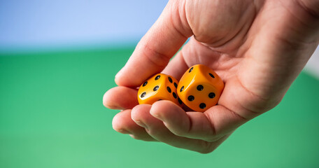 Hand is holding yellow dice over a green table