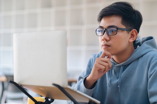 Young Collage Student Using Computer And Mobile Device Studying Online.