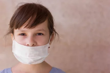 Poster Portrait of a young girl in a medical mask isolated on a wall background. Young woman patient, copy space © Albert Ziganshin