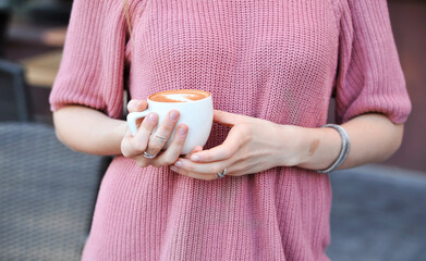 Beautiful woman in sweater drinks coffee outdoors 