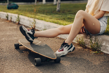 Teenage girl legs with a long board. Legs cropped.