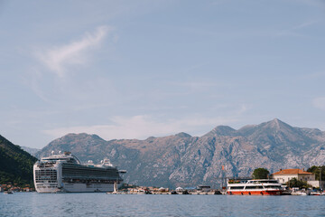Liner in the Gulf of Kotor in Montenegro, against the backdrop of mountains and blue sky with clouds.