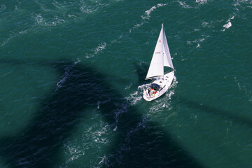 San Francisco / USA - March 2020: Aerial view of a sailing yacht in the shadow of the Golden Gate Bridge