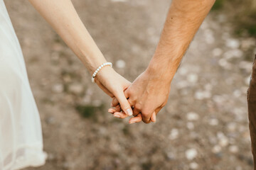 Close up of romantic couple holding hands standing on field