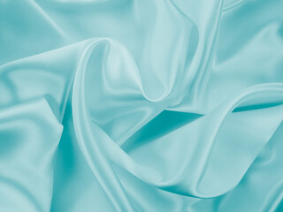 Beautiful elegant wavy turquoise silk or satin luxury cloth fabric texture, abstract background design.