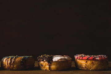 colorful donuts on a wooden table with a dark background