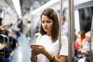 Focused girl using smartphone in subway wagon