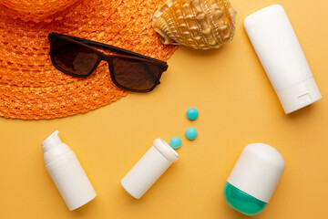 Sunglasses and hat with pills on orange background as a concept of vacation with protection on...