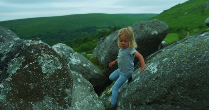 Preschooler climbing rocks on the moor in summer