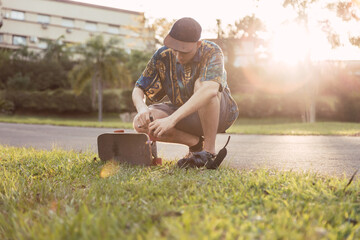 Cool skateboarder and photographer repairing his board  His camera's on the floor.  It's at sunset. © René Stevens