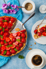 Delicious tart with strawberries on a blue painted background. Top view.