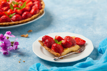 Delicious tart with strawberries on a blue painted background. Front view.