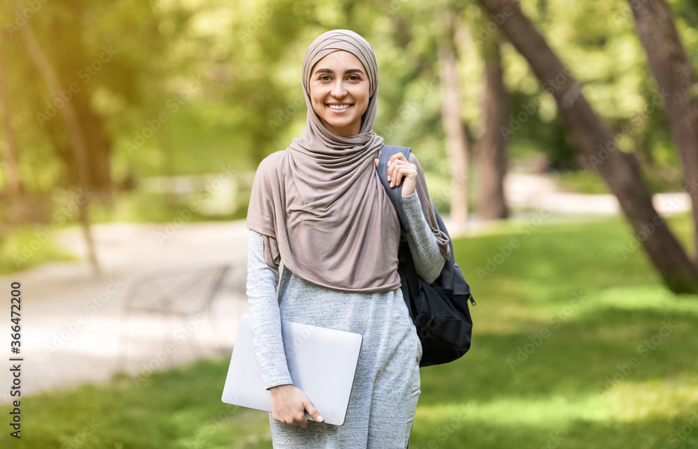 Wall mural attractive muslim woman with laptop posing at park