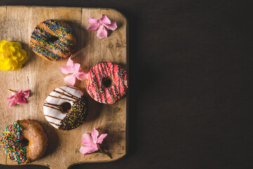 colorful donuts on a wooden table with a black background