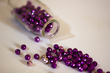 Purple beads pouring out of a glass bottle