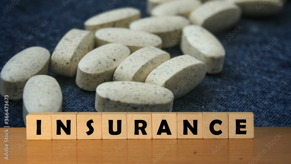 Poster insurance message word on a wooden desk on cube blocks with a medical objects.