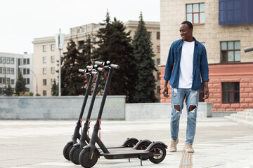 Guy standing and looking at rental motorized kick scooters