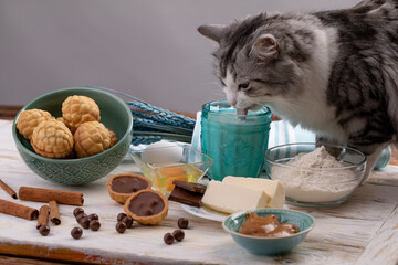 Homemade cookies with milk on a white wooden table. cat drinks milk from the glass among the...
