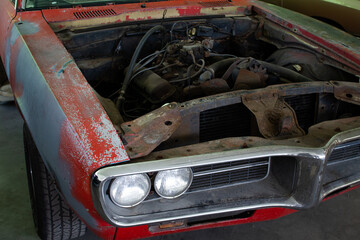 Photo of a muscle car to be restored. Taken from the front. Its powerful V8 engine is nice to see.