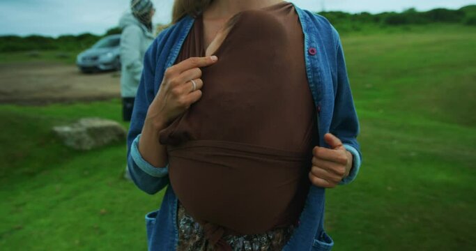 Mother with baby in sling walking on moor with grandparents