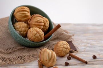 delicious walnut shaped shortbread sandwich cookies filled with sweet condensed milk and cinnamon on old wooden background, view from above, close-up