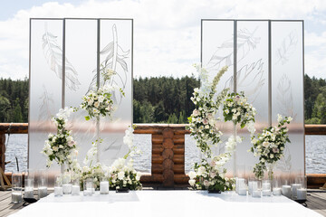Wedding ceremony with white transparent screens and fresh white flowers and candles