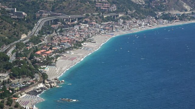 Aerial view of Letojanni seen from Taormina. Beach, town and highway. Footage 4k