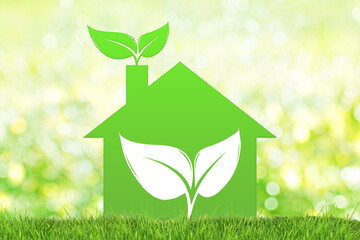 Green house symbol with leaves on green defocused background. Green house concept.