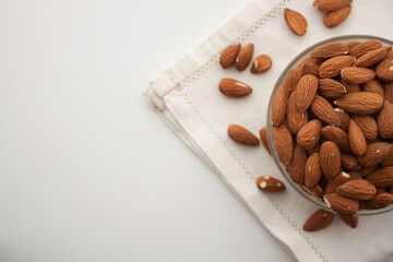Almond in a bowl on white serviette in the right side of white background
