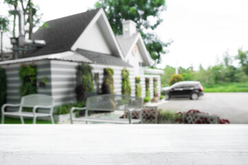 Empty wooden desk space and blurry background of house for product display montage.