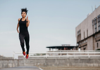 Running, jump and flight. Athletic slim african american girl in fashionable sport uniform froze in air