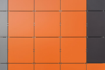 The wall is lined with colored ceramic tiles of orange, gray and black color. Minimalism, background