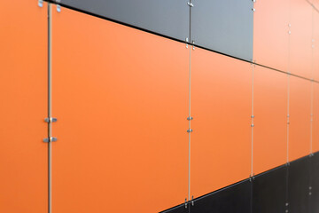 The wall is lined with colored ceramic tiles of orange, gray and black color. Minimalism, background