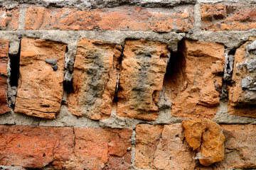 A wall of very old brick red-orange and brown with destruction. Texture
