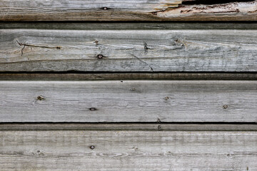 The texture of the building's surface is made of old wooden planks of gray and brown. Horizontal direction of boards