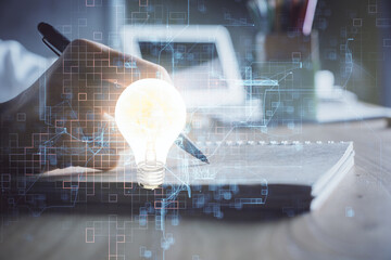 Drawing bulb over woman's hands taking notes background. Concept of idea. Double exposure