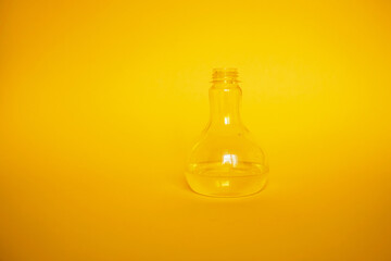 Glass vase is half full of water. Yellow background, minimalism monochromaic composition
