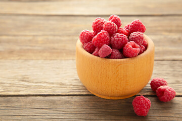 Ripe raspberries in wooden bowl on grey background. Top view