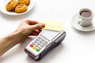 Payment by credit card. Hand hold card near terminal on white table