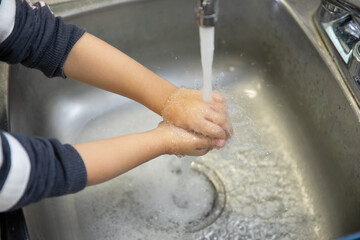 Enfant se lavant les mains sous l'eau du robinet