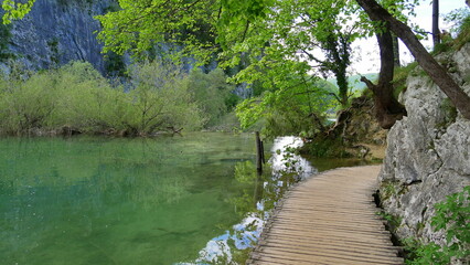 Fototapeta na wymiar Holzsteg entlang einenm See und Felsen in den Plitvicer Seen, Kroatien, Südosteuropa