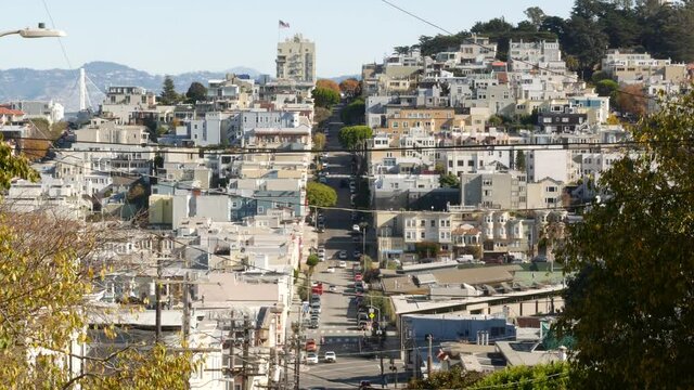Iconic hilly street and crossroads in San Francisco, Northern California, USA. Steep downhill road and pedestrian walkway. Downtown real estate, victorian townhouses abd other residential buildings.