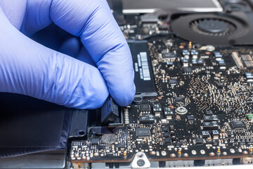 Service engineer install plug in new battery to the laptop. Repairing laptop concept. Close up view.