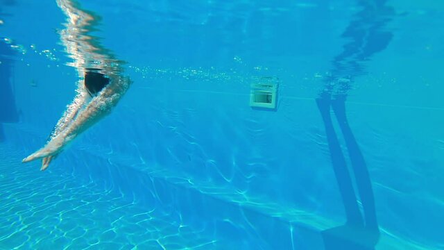 Underwater shooting. Girl dive in blue swimming pool.