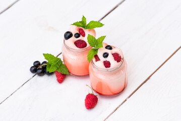 Yogurt with raspberries, currants and mint leaves on the table.
