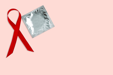 Condom and red ribbon on pink background with copy space.Condom use to reduce probability of...