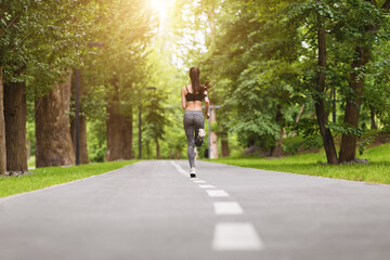 Sports Motivation. Back view of fit woman jogging in morning park