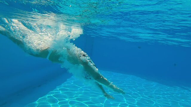 Underwater shooting. Girl dive in blue swimming pool.