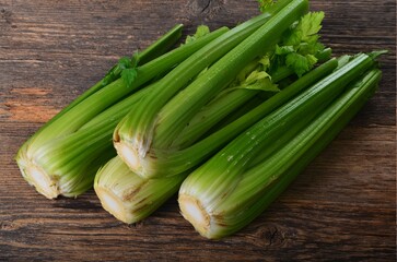 Obraz premium Bunch of fresh celery stalk with leaves on old wooden background
