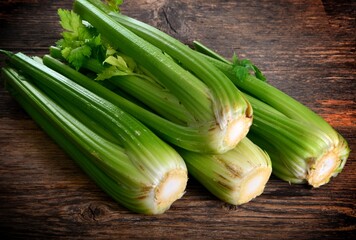Bunch of fresh celery stalk with leaves on old wooden background